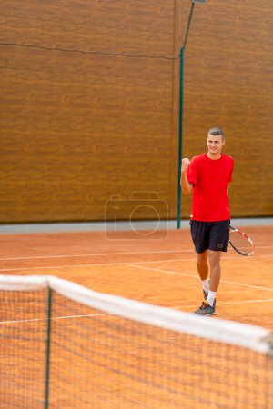 Téléchargez les photos : Portrait d'un jeune joueur de tennis professionnel se réjouit de la victoire à la compétition du tournoi sur le terrain ouvert gagnant jeu de sport - en image libre de droit