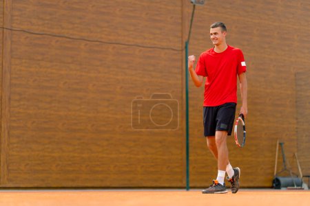 Téléchargez les photos : Portrait d'un jeune joueur de tennis professionnel se réjouit de la victoire à la compétition du tournoi sur le terrain ouvert gagnant jeu de sport - en image libre de droit