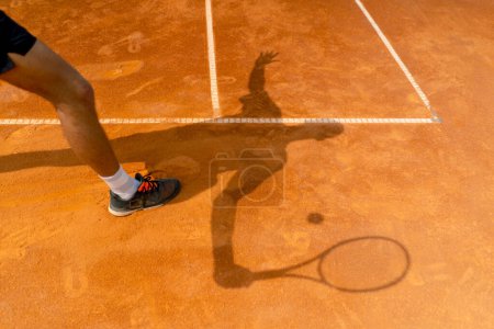 Téléchargez les photos : L'ombre d'un joueur de tennis ou d'un entraîneur sur un terrain de sport ouvert en terre battue orange - en image libre de droit
