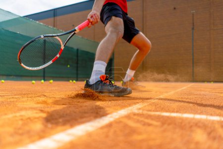 Téléchargez les photos : Gros plan du pied d'un joueur de tennis ou d'un instructeur sur un terrain extérieur poussière de sol s'élevant près de la chaussure - en image libre de droit