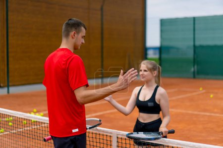 Photo for Young man and woman shaking hands before the start of a tennis game on open court sports players opponents - Royalty Free Image