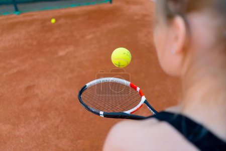 Téléchargez les photos : Jeune fille débutant joueur de tennis frapper la balle avec une raquette sur le terrain de pratique et d'apprendre à frapper et servir le sport passe-temps gros plan - en image libre de droit