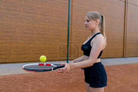 Foto de Joven chica principiante tenista golpea la pelota con una raqueta en los trenes de pista y aprende a golpear servir pasatiempo deportivo - Imagen libre de derechos