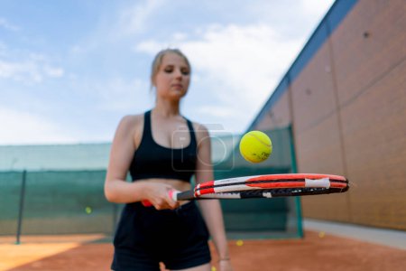 Foto de Joven chica principiante tenista golpea la pelota con una raqueta en los trenes de pista y aprende a golpear servir pasatiempo deportivo - Imagen libre de derechos