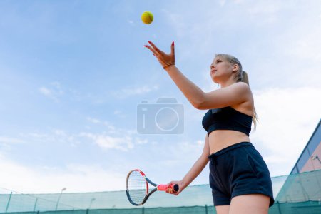 Téléchargez les photos : Jeune fille débutant joueur de tennis frappe la balle avec une raquette sur les trains de court et apprend à frapper servir passe-temps sportif - en image libre de droit