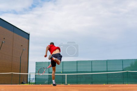 Foto de Joven entrenador jugador profesional en las prácticas de tenis al aire libre golpes con raqueta pelota de tenis - Imagen libre de derechos
