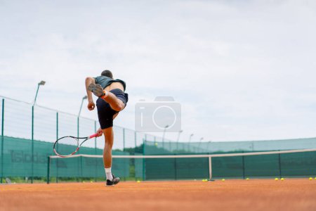 Téléchargez les photos : Jeune entraîneur de joueur professionnel sur le court de tennis en plein air pratique coups avec raquette balle de tennis - en image libre de droit