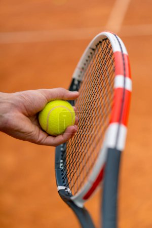 Téléchargez les photos : Jeune entraîneur ou joueur tenant raquette de tennis et ballon tout en jouant sur le terrain gros plan - en image libre de droit