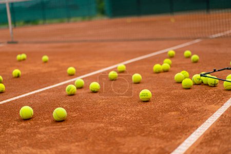 Foto de Pequeñas bolas brillantes se encuentran pista de tenis de arcilla entrenamiento deportivo profesional hobby jugar al aire libre - Imagen libre de derechos