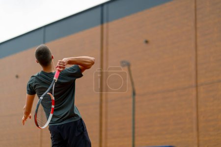 Photo for Young professional player coach on outdoor tennis court practices strokes with racket tennis ball - Royalty Free Image
