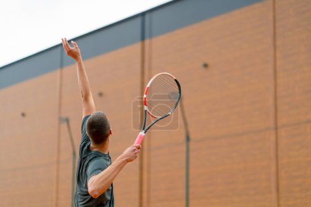 Téléchargez les photos : Jeune entraîneur de joueur professionnel sur le court de tennis en plein air pratique coups avec raquette balle de tennis - en image libre de droit