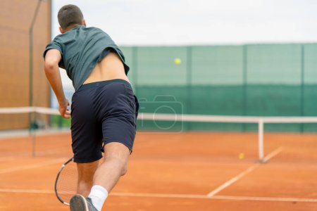 Photo for Young professional player coach on outdoor tennis court practices strokes with racket tennis ball - Royalty Free Image