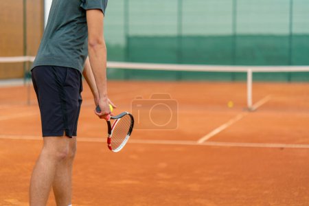 Foto de Joven entrenador jugador profesional en las prácticas de tenis al aire libre golpes con raqueta pelota de tenis - Imagen libre de derechos