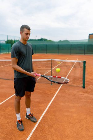 Foto de Joven entrenador de tenis golpeando la pelota con una raqueta en la cancha de tenis preparándose para el estilo de vida deportivo de competición - Imagen libre de derechos