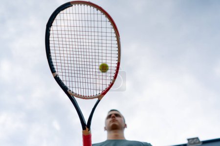 Foto de Primer plano joven entrenador de tenis golpeando la pelota con una raqueta en la cancha de tenis preparándose para el estilo de vida deportivo de la competencia - Imagen libre de derechos