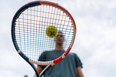 Foto de Primer plano joven entrenador de tenis golpeando la pelota con una raqueta en la cancha de tenis preparándose para el estilo de vida deportivo de la competencia - Imagen libre de derechos