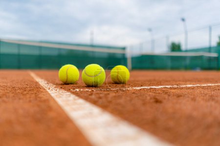 Foto de Pequeñas bolas brillantes se encuentran pista de tenis de arcilla entrenamiento deportivo profesional hobby jugar al aire libre - Imagen libre de derechos