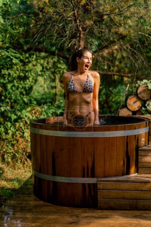Téléchargez les photos : Jeune fille sportive prend un bain dans l'eau froide dans une piscine extérieure en vacances dans les bois - en image libre de droit