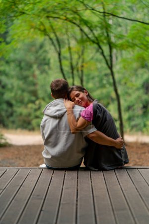 Photo for Man and woman in love sitting with their backs to the camera on a terrace overlooking the forest with plaids cuddling and talking - Royalty Free Image