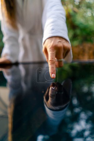 Téléchargez les photos : Gros plan des mains abaissées dans l'eau pour vérifier la température de l'eau avant de nager dans une piscine extérieure - en image libre de droit