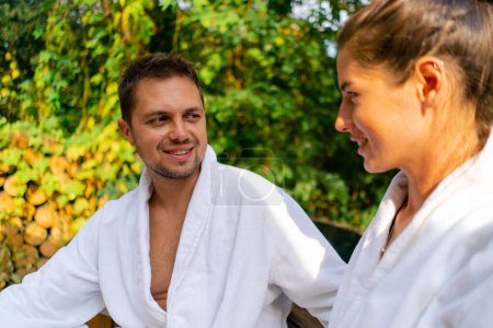 Téléchargez les photos : Un jeune beau couple amoureux en robes de chambre se prépare à nager dans une piscine extérieure dans les bois - en image libre de droit