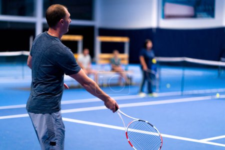 Photo for A man on a closed blue tennis court with a racket deflects the opponent's blows persistently wants win - Royalty Free Image