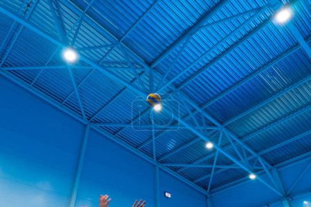 Foto de Una pelota de voleibol en el aire vuela sobre la red y vuela a una parte de los oponentes que están tratando de repeler con sus manos juego de competición - Imagen libre de derechos
