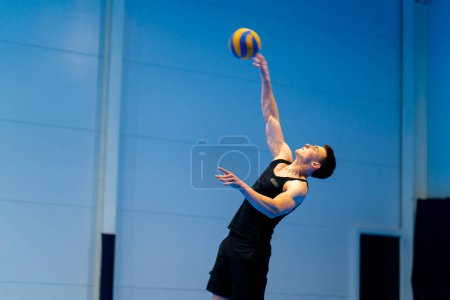 Foto de Un joven deportista bombeado durante un partido de voleibol o partido golpea la pelota con la mano después de servir oponente - Imagen libre de derechos