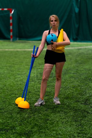 Photo for Portrait of a smiling young girl who loves football standing on field holding sports equipment in her hands after training - Royalty Free Image