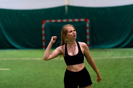 Téléchargez les photos : Jeune fille de football féminin se réjouit sur le terrain de football après avoir marqué un but contre le but de l'adversaire jeu de sport - en image libre de droit