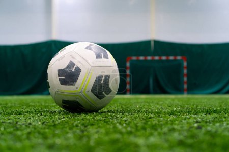 Téléchargez les photos : Un ballon de football noir et blanc se trouve sur un terrain de sport sur un gazon synthétique vert avant le début de la partie de sport gros plan - en image libre de droit
