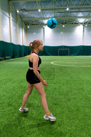 Téléchargez les photos : Soccer féminin jeune fille entraîne la coordination sur le terrain de soccer intérieur frapper le ballon avec sa tête - en image libre de droit