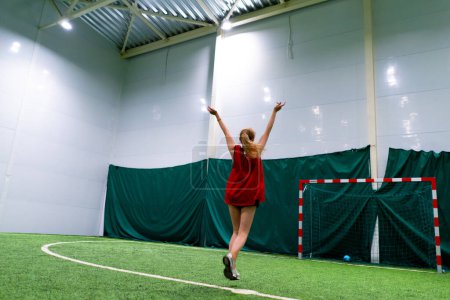 Photo for Women's football young girl rejoices on the football field after scoring goal against the opponent's goal back view sports game - Royalty Free Image