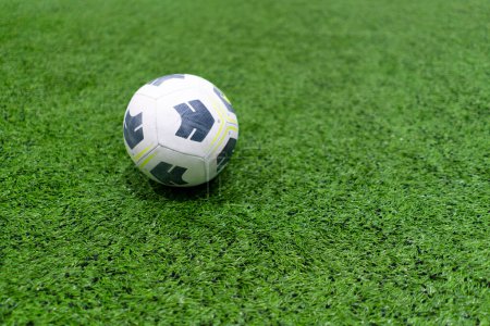 Foto de Una pelota de fútbol blanco y negro se encuentra en un campo de deportes en un césped sintético verde antes del inicio del juego de deportes de cerca - Imagen libre de derechos