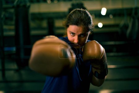Foto de Retrato de una mujer con guantes de boxeo posando en una pelea descarada y competitiva en un ring de boxeo antes de pelear con un oponente - Imagen libre de derechos