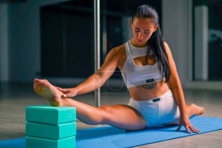 Photo for Young beautiful flexible girl trainer doing stretching before pole dancing sitting twine training sport - Royalty Free Image