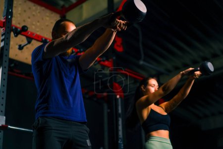 Téléchargez les photos : Jeunes athlètes conduisent un entraînement de groupe dans la salle de gym faire des exercices avec des kettlebells se préparer pour la compétition - en image libre de droit