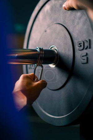 Téléchargez les photos : Entraîneur d'athlète masculin ajoute du poids à l'haltère dans la salle de gym augmente la charge sur le corps du bodybuilder gros plan - en image libre de droit