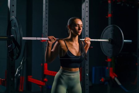 Photo for Portrait of young beautiful focused fitness woman doing heavy shoulder press exercise with barbell gym training muscle groups - Royalty Free Image