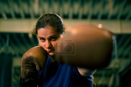 Photo for Portrait of a woman in boxing gloves posing in a cheeky and competitive fight in a boxing ring before fight with an opponent - Royalty Free Image