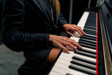 Photo for Close-up of a woman's fingers in silver rings playing a lyrical melody on white and black piano keys - Royalty Free Image