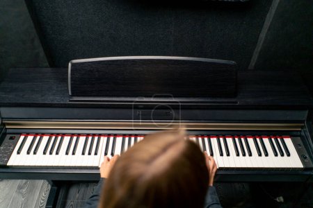 Téléchargez les photos : Le plan ci-dessus est d'une jeune fille assise au piano et jouant une belle mélodie lyrique - en image libre de droit