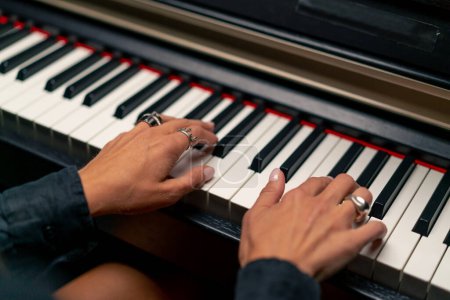 Photo for Close-up of a woman's hands in silver rings playing a beautiful lyrical melody on the piano keys - Royalty Free Image
