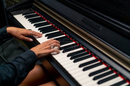 Foto de Primer plano de las manos de una mujer en anillos de plata tocando una hermosa melodía lírica en las teclas del piano - Imagen libre de derechos