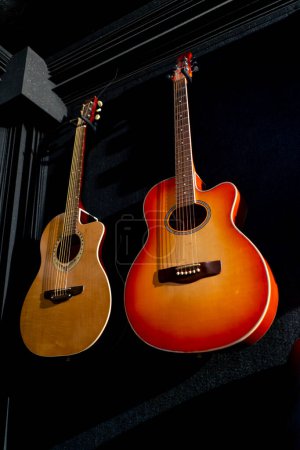 Foto de Guitarra acústica clásica de madera colgada de la pared en un estudio de música para grabar nuevas bandas sonoras - Imagen libre de derechos