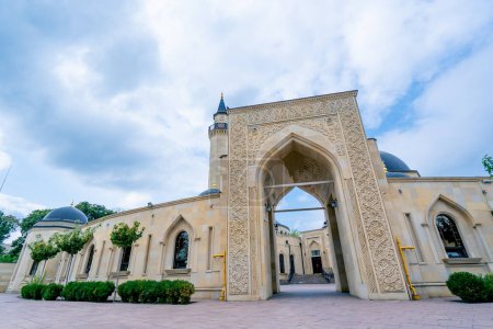 Téléchargez les photos : Belle entrée cosy d'une mosquée musulmane entourée d'une arche avec des ornements islamiques contre le ciel bleu - en image libre de droit