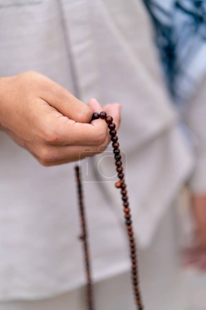 Foto de Manos masculinas de un hombre islámico sosteniendo un rosario durante la oración de conversión y adoración de Allah - Imagen libre de derechos