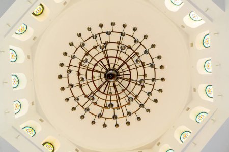 Téléchargez les photos : Un magnifique lustre en or de luxe est accroché dans le hall d'une mosquée musulmane sur un plafond blanc - en image libre de droit