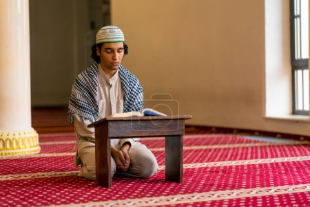 Photo for A Muslim man sits in silence on the carpet in the holy mosque prays reads the Koran and turns to Allah - Royalty Free Image