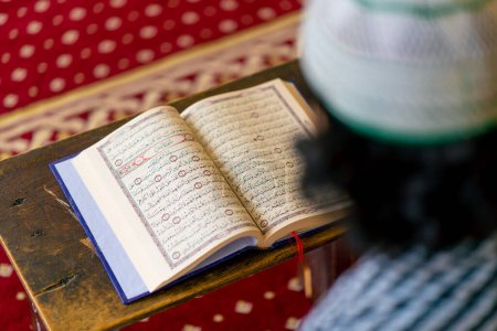 Téléchargez les photos : Vue arrière d'un musulman solitaire récitant le Saint Coran dans une mosquée pour guérir son âme pendant le Ramadan - en image libre de droit